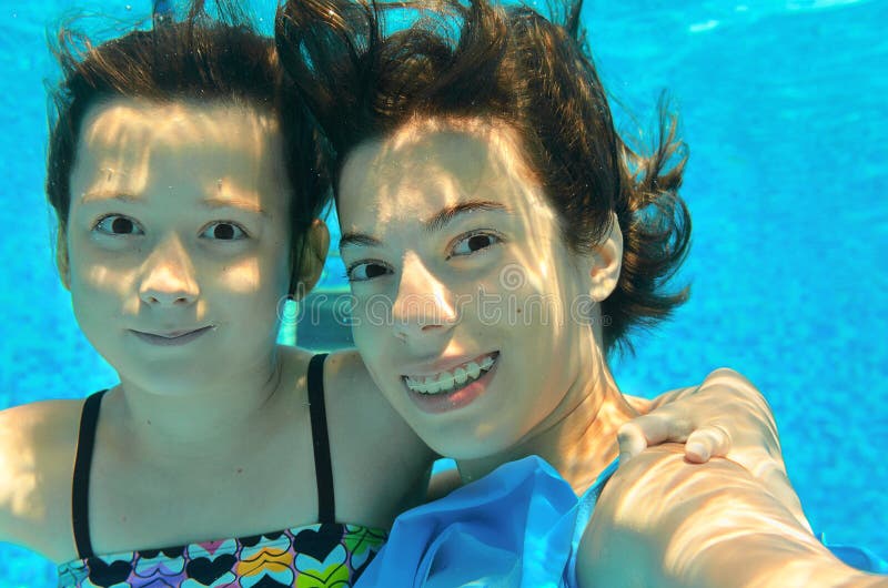 As crianças nadam na associação subaquática, fazendo o selfie, meninas ativas felizes têm o divertimento, esporte das crianças foto de stock As crianças nadam na associação subaquática, fazendo o selfie, meninas ativas felizes têm o divertimento, esporte das crianças foto de stock