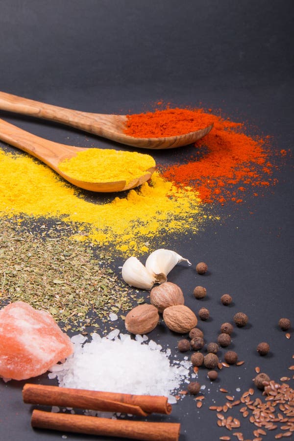 As especiarias e as ervas naturais dispersaram no fundo escuro Ingredientes naturais e bio para cozinhar foto de stock As especiarias e as ervas naturais dispersaram no fundo escuro Ingredientes naturais e bio para cozinhar foto de stock
