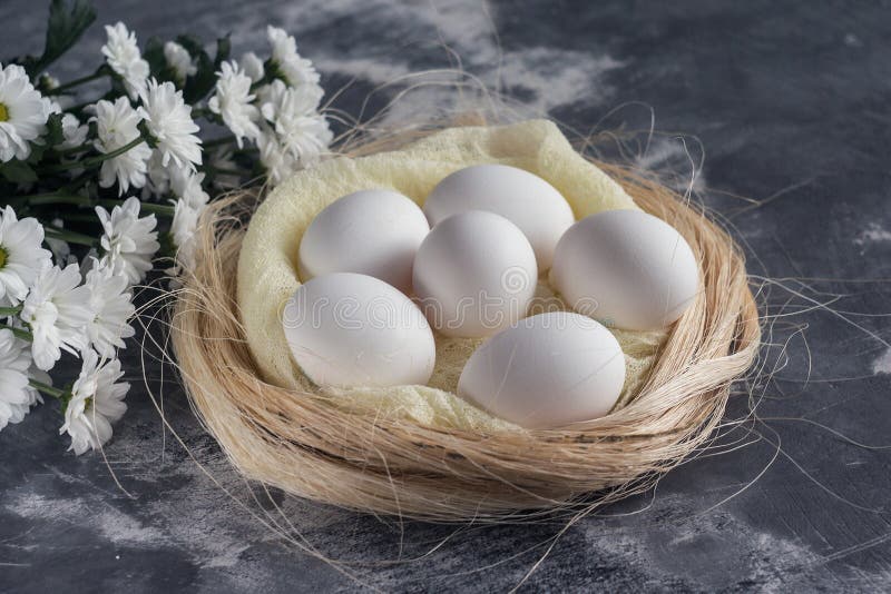 As flores brancas com galinha eggs no ninho no fundo de pedra cinzento Conceito do feriado da mola e da Páscoa com espaço da cópi foto de stock As flores brancas com galinha eggs no ninho no fundo de pedra cinzento Conceito do feriado da mola e da Páscoa com espaço da cópi foto de stock