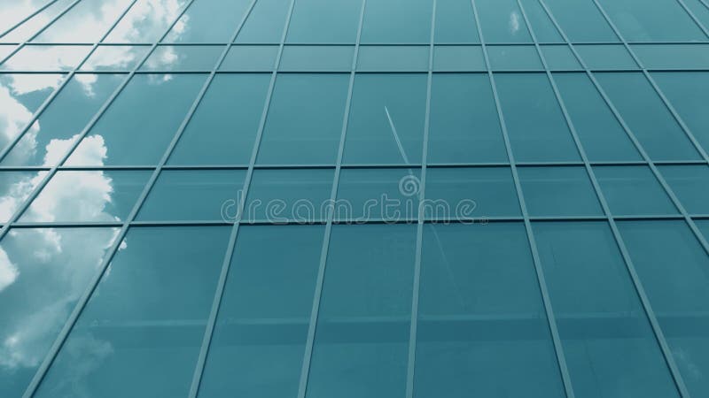 As janelas de vidro modernas da fachada refletem o plano e nuvens de voo fotografia de stock royalty free As janelas de vidro modernas da fachada refletem o plano e nuvens de voo fotografia de stock royalty free