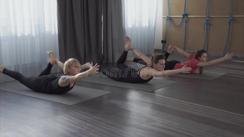 As jovens mulheres aprendem asanas da ioga a fim tornar-se mais flexíveis e plásticas