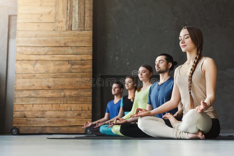 Young women and men in yoga class, meditation exercises. Lotus pose for relaxation. Healthy lifestyle in fitness club, crop, copy space. Young women and men in yoga class, meditation exercises. Lotus pose for relaxation. Healthy lifestyle in fitness club, crop, copy space