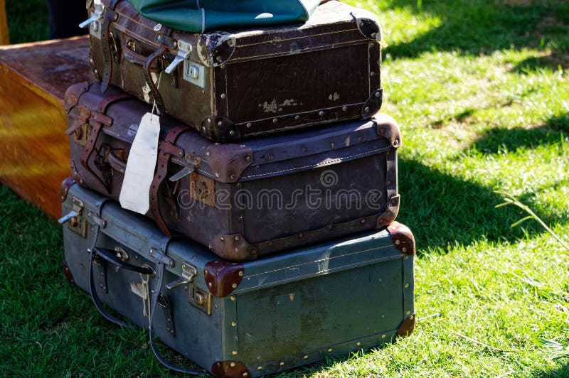 A pile of old fashioned rectangular suitcases piled up on the grass. A pile of old fashioned rectangular suitcases piled up on the grass.