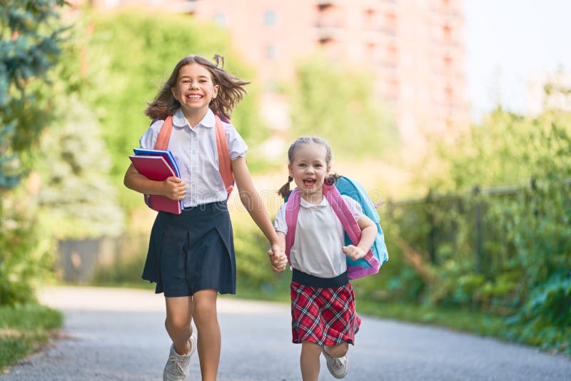 As meninas com trouxa estão indo educar fotografia de stock As meninas com trouxa estão indo educar fotografia de stock