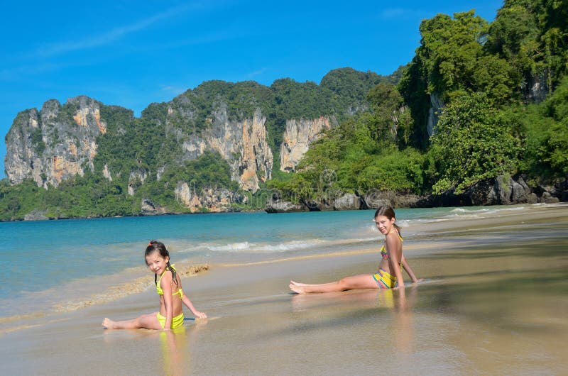 As meninas felizes jogam no mar na praia tropical foto de stock royalty free As meninas felizes jogam no mar na praia tropical foto de stock royalty free