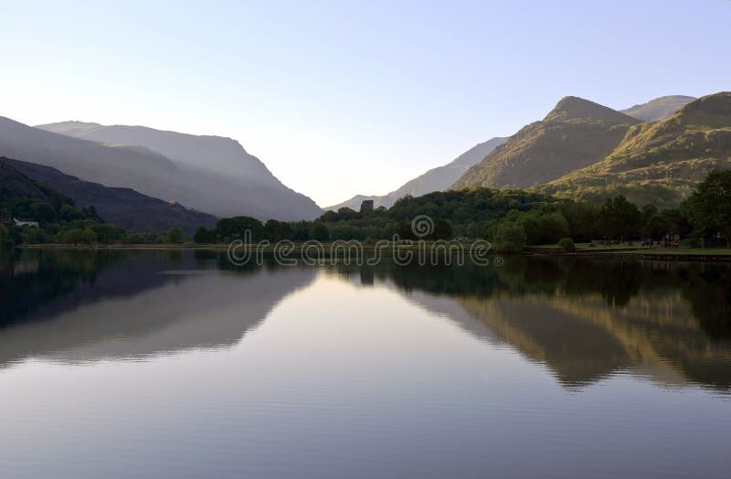 As montanhas bonitas de Galês refletiram em águas de um destilador do lago Llyn Padarn, Llan Beris Gales
