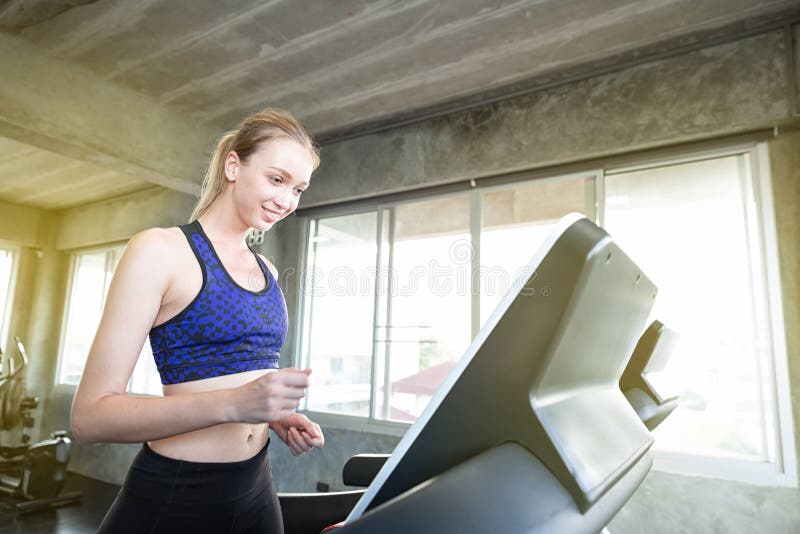 As mulheres brancas estão exercitando em máquinas do exercício Jovens que correm na escada rolante no gym Exercício caucasiano no foto de stock royalty free As mulheres brancas estão exercitando em máquinas do exercício Jovens que correm na escada rolante no gym Exercício caucasiano no foto de stock royalty free