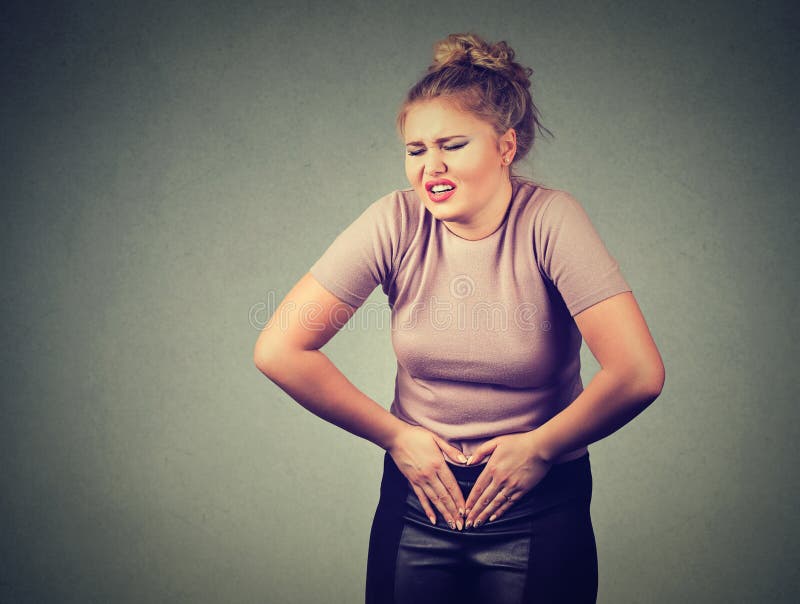 As mãos da jovem mulher no estômago que tem dores más causam dor Intoxicação alimentar, gripe, grampos fotos de stock royalty free As mãos da jovem mulher no estômago que tem dores más causam dor Intoxicação alimentar, gripe, grampos fotos de stock royalty free
