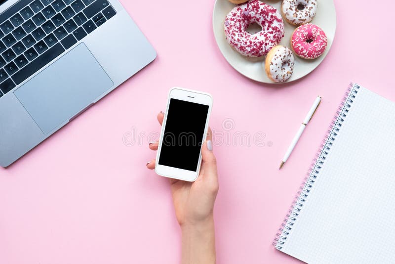 As mãos da mulher do quadro que guardam o smartphone branco com copyspace preto no fundo cor-de-rosa com outros acessórios Negóci fotografia de stock royalty free As mãos da mulher do quadro que guardam o smartphone branco com copyspace preto no fundo cor-de-rosa com outros acessórios Negóci fotografia de stock royalty free