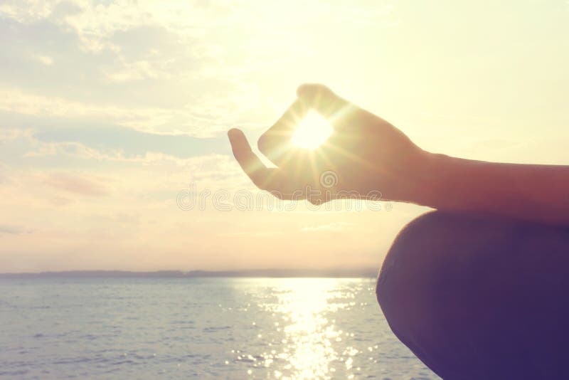 As mãos da mulher que meditam sobre uma ioga levantam na praia fotos de stock As mãos da mulher que meditam sobre uma ioga levantam na praia fotos de stock