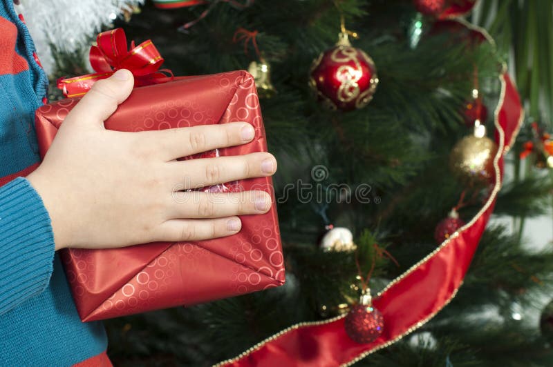 As mãos das crianças que guardaram o presente do Natal imagens de stock royalty free As mãos das crianças que guardaram o presente do Natal imagens de stock royalty free
