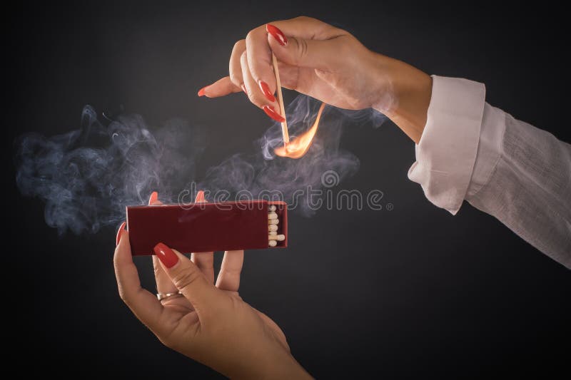 Womens hands ignite big matches for a tompus cigare or a fireplace. Studio shoot. Womens hands ignite big matches for a tompus cigare or a fireplace. Studio shoot