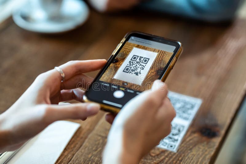 As mãos de uma jovem usando o smartphone para digitalizar o código qr para selecionar o menu de comida no restaurante