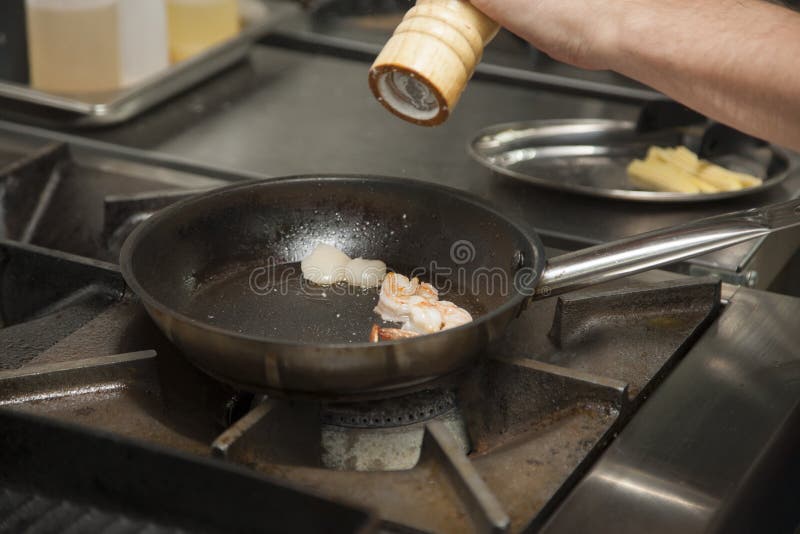 As mãos do cozinheiro, grelhando o camarão foto de stock As mãos do cozinheiro, grelhando o camarão foto de stock