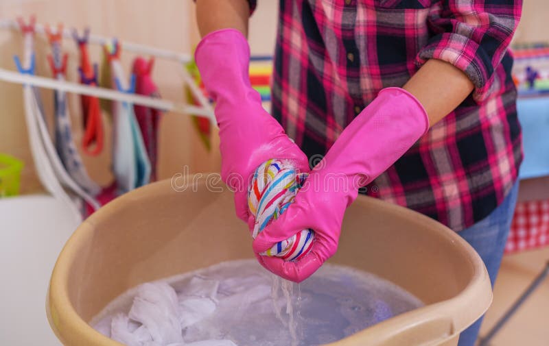 Women`s hands wash clothes in the container. Close-up. Women`s hands wash clothes in the container. Close-up.