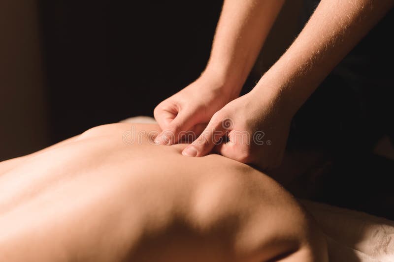 As mãos do ` s dos homens fazem uma massagem terapêutica do pescoço para uma menina que encontra-se em um sofá da massagem em uns foto de stock royalty free As mãos do ` s dos homens fazem uma massagem terapêutica do pescoço para uma menina que encontra-se em um sofá da massagem em uns foto de stock royalty free