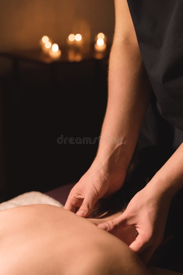 As mãos do ` s dos homens fazem uma massagem terapêutica do pescoço para uma menina que encontra-se em um sofá da massagem em uns fotografia de stock royalty free As mãos do ` s dos homens fazem uma massagem terapêutica do pescoço para uma menina que encontra-se em um sofá da massagem em uns fotografia de stock royalty free