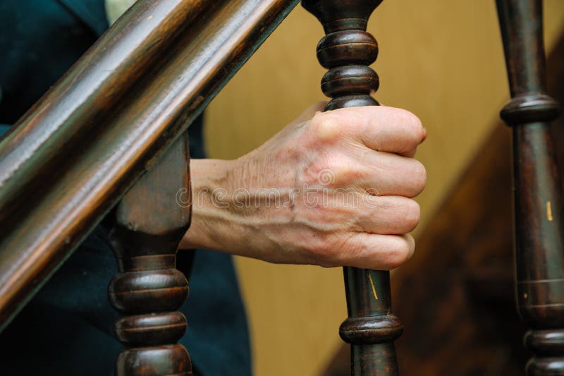 As mãos enrugadas mulher adulta prendem o corrimão fotografia de stock As mãos enrugadas mulher adulta prendem o corrimão fotografia de stock