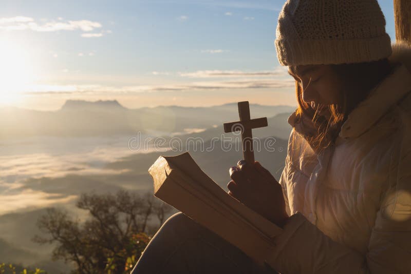 As mãos que guardam de madeira cruzam-se sobre a BÃblia Sagrada aberta no fundo da montanha com nascer do sol, spirtuality e re foto de stock As mãos que guardam de madeira cruzam-se sobre a BÃblia Sagrada aberta no fundo da montanha com nascer do sol, spirtuality e re foto de stock