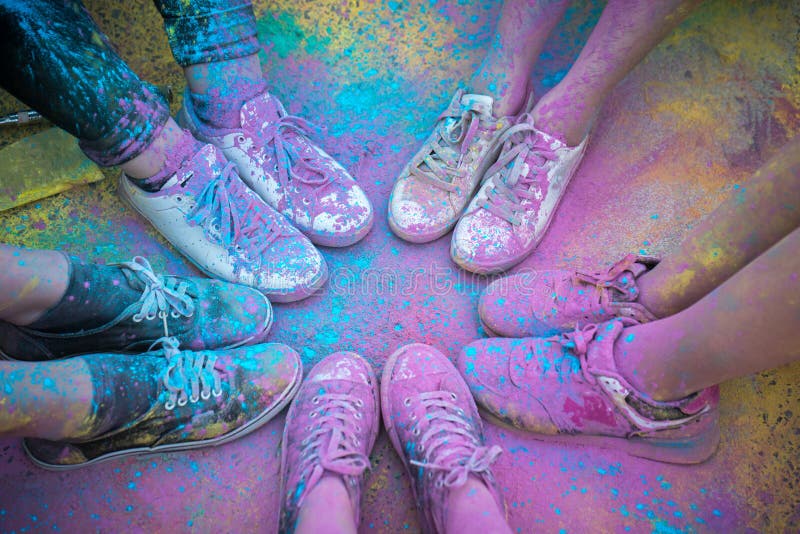 As sapatas e os pés coloridos dos adolescentes no evento da corrida da cor