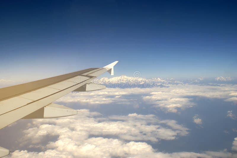 Asa de um avião que voa acima da nuvem com vista ao fundo do Monte Everest, conceito de viagem fotos de stock royalty free Asa de um avião que voa acima da nuvem com vista ao fundo do Monte Everest, conceito de viagem fotos de stock royalty free