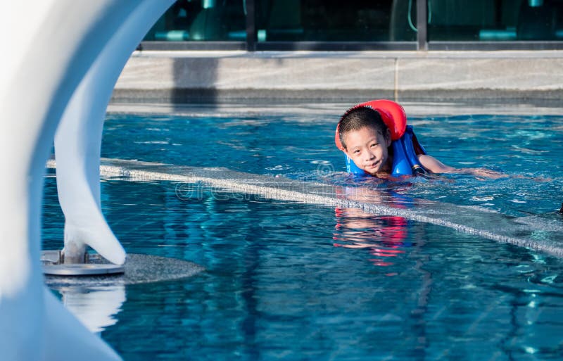 Asain-Junge in einem Swimmingpool, der eine Schwimmweste trägt lizenzfreie stockbilder Asain-Junge in einem Swimmingpool, der eine Schwimmweste trägt lizenzfreie stockbilder