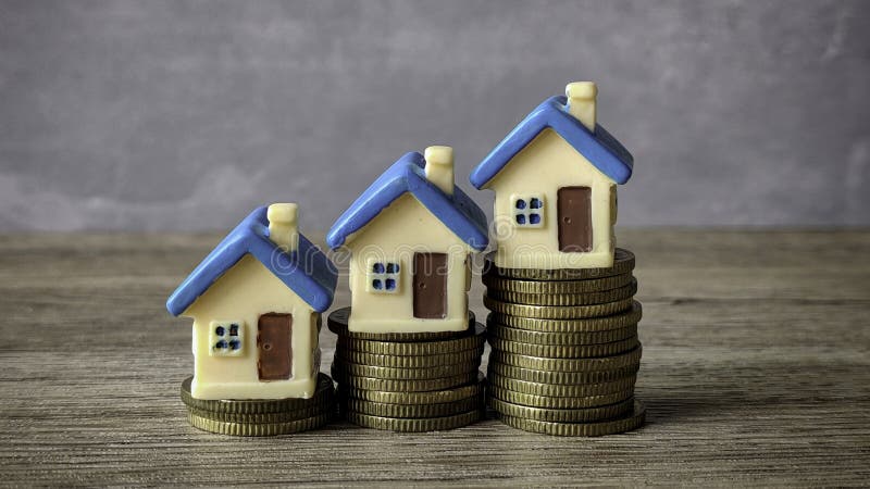Ascenso de monedas de oro apiladas con una casa en miniatura encima de cada fotos de archivo