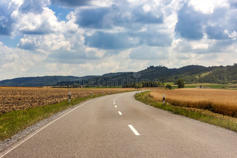 Asfalte el camino rural del país en Alemania a través del campo verde