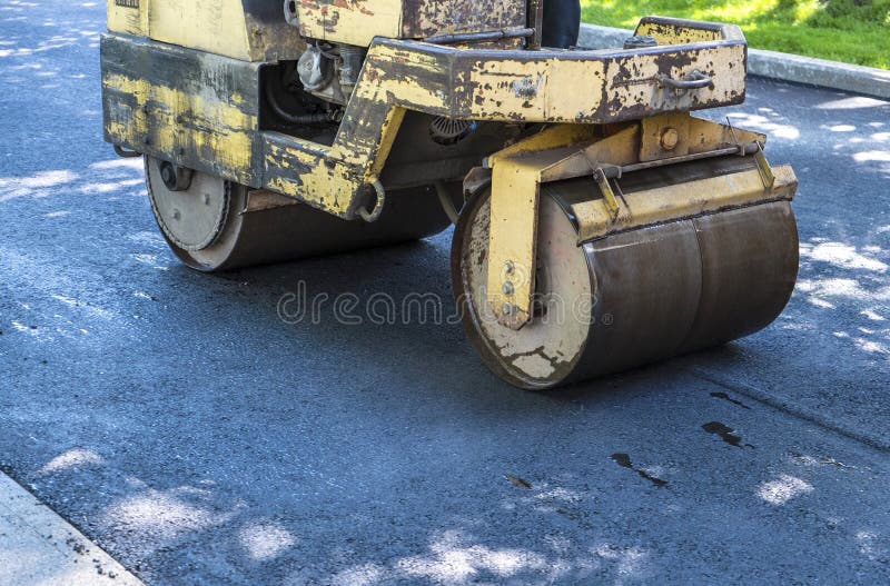 Asfalto di rotolamento su una strada privata fotografie stock Asfalto di rotolamento su una strada privata fotografie stock