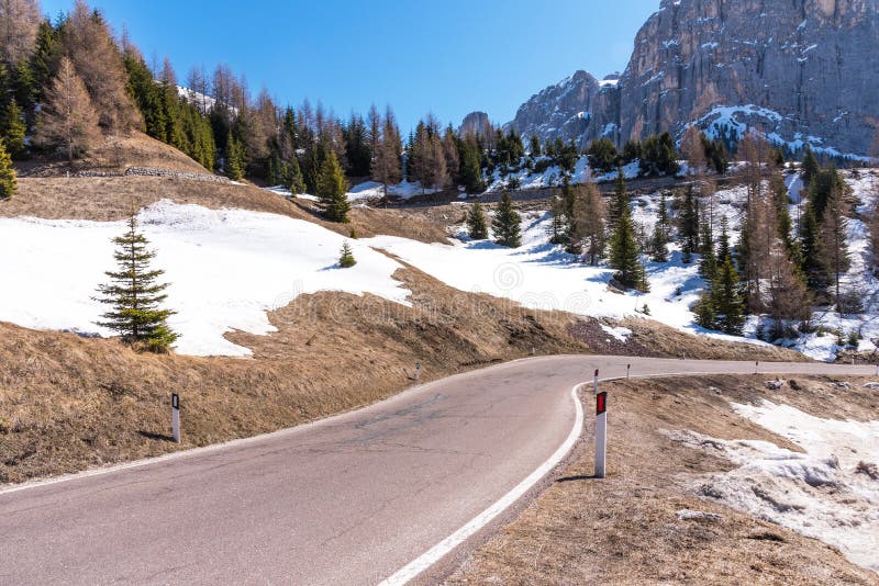 Asfaltväg i dolomitesna på våren Berg och skogar mot en blå himmel royaltyfri fotografi Asfaltväg i dolomitesna på våren Berg och skogar mot en blå himmel royaltyfri fotografi