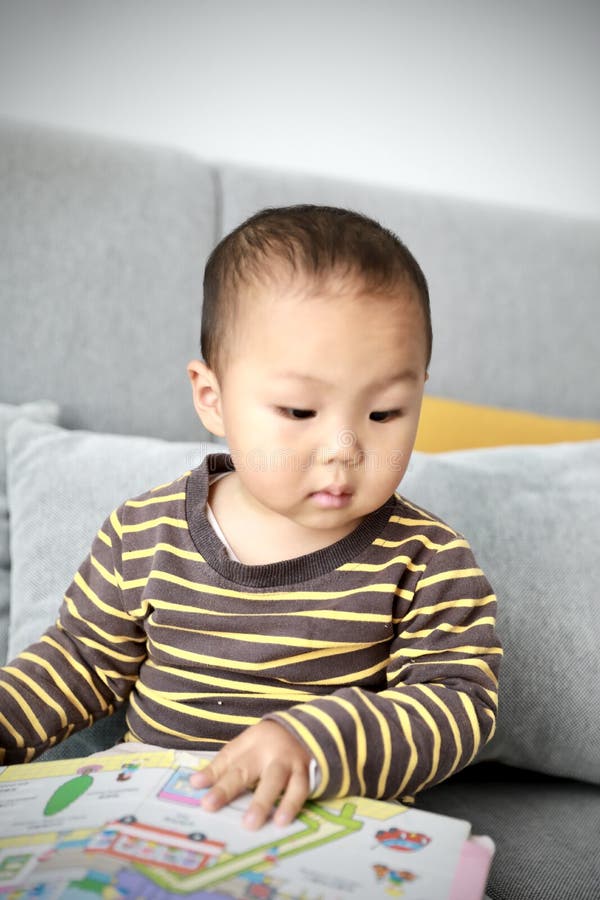 Asia Chinese Little Boy Toddler Child Sit On Couch Read Book At Home