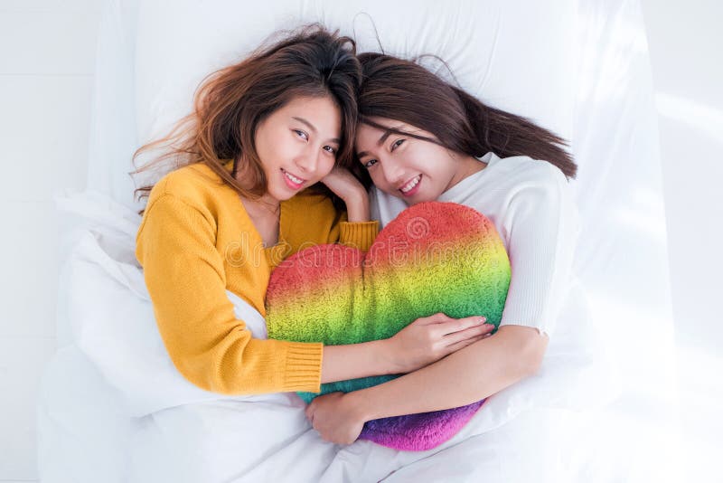 Asia Lesbian Lgbt Couple Lay On Bed And Hug Rainbow Color Pillow Stock