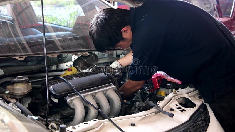 Asian auto mechanic checking and repair engine.