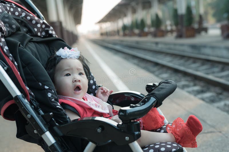 Asian baby girl sitting in stroller in railway station. stock images Asian baby girl sitting in stroller in railway station. stock images