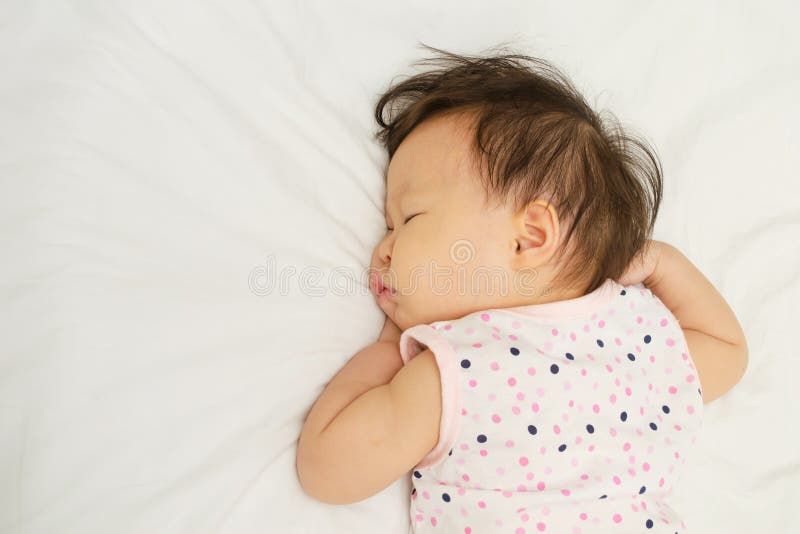 Asian baby girl sleeping on bed