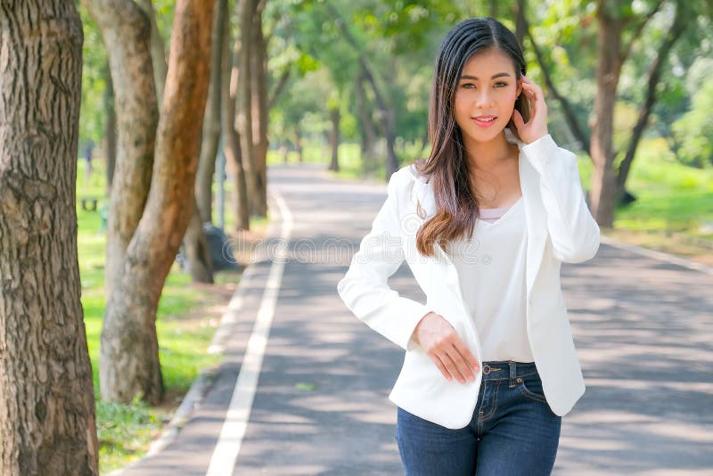 Asian beautiful business woman with white suit stand on the road in the garden with the concept the success way for professional royalty free stock photography Asian beautiful business woman with white suit stand on the road in the garden with the concept the success way for professional royalty free stock photography