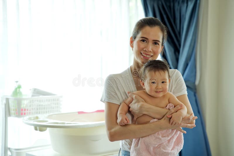 Asian beautiful mother holding little cute baby after taking a bath. stock photo Asian beautiful mother holding little cute baby after taking a bath. stock photo
