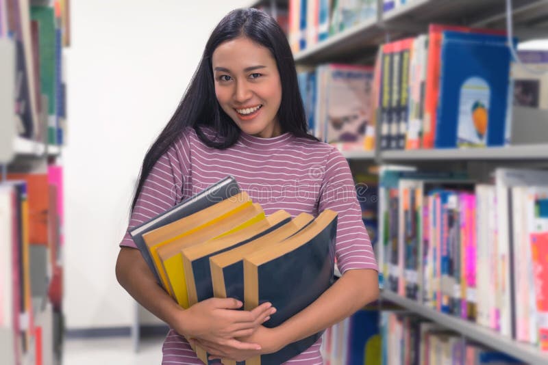 Asian beautiful young woman student holding stack of old books i stock photo Asian beautiful young woman student holding stack of old books i stock photo