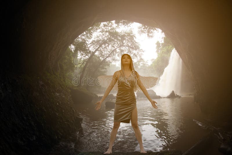Asian beauty Standing post in a cave In front of the waterfall.