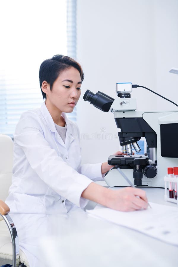 Asian biologist studying cells with microscope royalty free stock image Asian biologist studying cells with microscope royalty free stock image