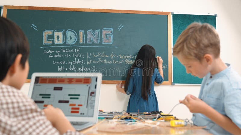 Asian boy coding program while caucasian friend fixing electric board at STEM class. Energetic student standing blackboard while writing coding engineering prompt and programing AI software. Pedagogy. Program coding working stock images, royalty-free photos and pictures