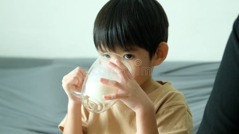 Asian boy drinking milk from a glass with a bright smile. stock video footage