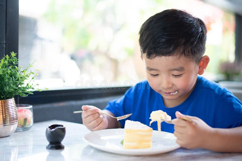 Asian boy eating cake in bakery shop or cafe royalty free stock photo Asian boy eating cake in bakery shop or cafe royalty free stock photo