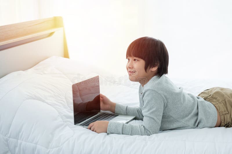 Asian Boy in Front of Laptop Computer Lay on Bed with Smile Stock Image