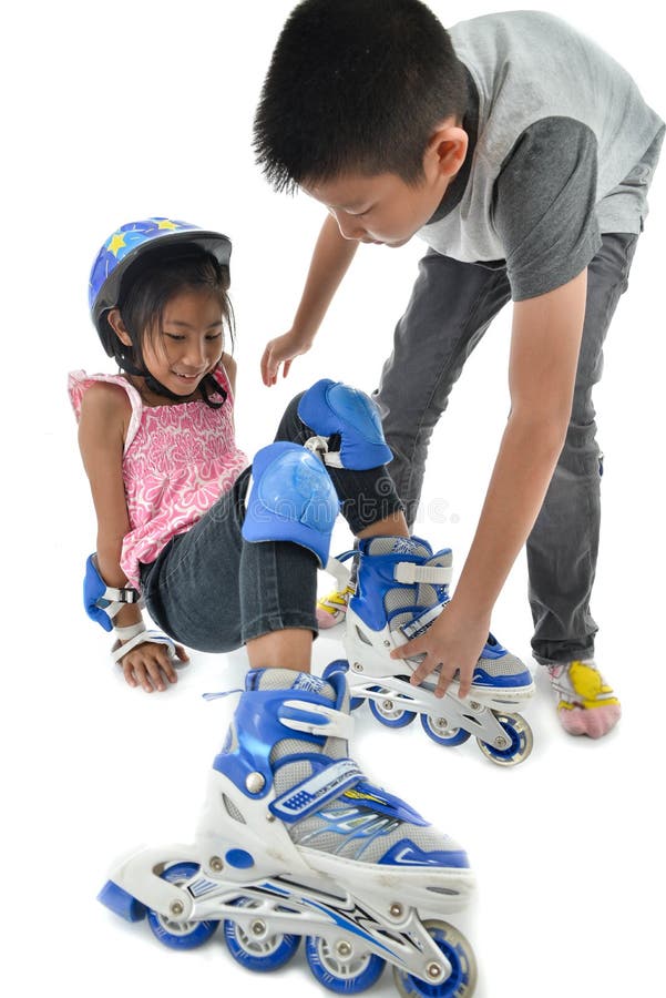 Asian boy help his sister whie learning roller skates on white b