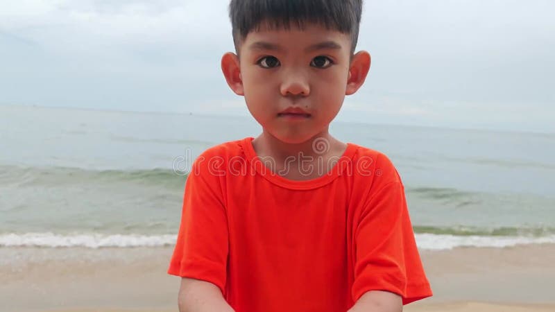 Asian boy playing in the sand at the beach. stock video footage