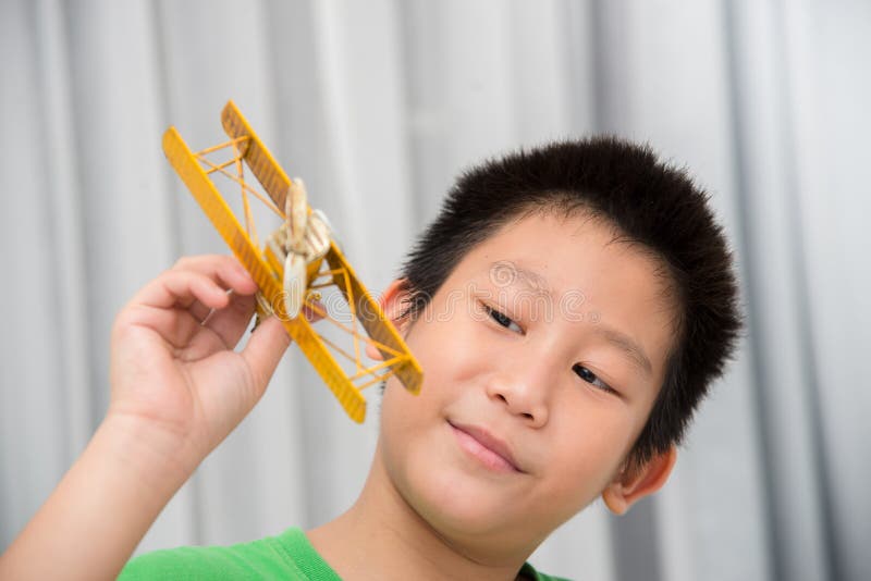 Asian boy playing yellow vintage plane at home