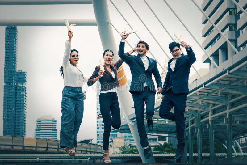 Asian business people with winner certificate on hands jump up together with excite for their team achievement to win the business