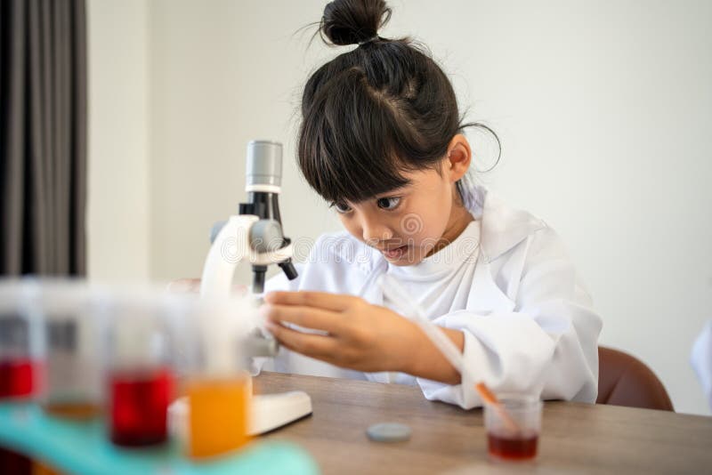 Asian Children in Lab Coat Using a Microscope for a Science Experiment