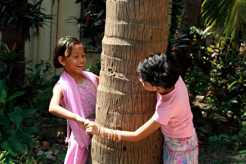 Two Asian girls playing a game of hide and seek in the park. Two Asian girls playing a game of hide and seek in the park.